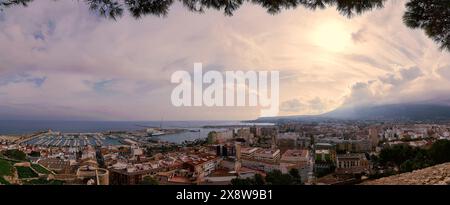 Fotografia panoramica con risoluzione igh che mostra la splendida città costiera di Denia, in Spagna, inondata dalla calda luce del sole e ornata di nuvole soffici Foto Stock