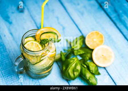 Un cocktail estivo e rinfrescante al cetriolo e basilico in una tazza di vetro trasparente su un tavolo di legno blu. Messa a fuoco selezionata. Foto di alta qualità Foto Stock