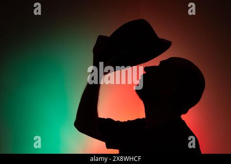 Ritratto in studio di un uomo con cappello in silhouette. Isolato su sfondo colorato. Foto Stock