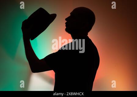Ritratto in studio di un uomo con cappello in silhouette. Isolato su sfondo colorato. Foto Stock