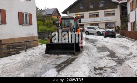 Schwere Unwetter mit jede Menge Hagel ziehen seit den Abendstunden durch Südbayern. Betroffen vor allem die alpennahen Gebiete. Eine Superzelle zog von Füssen quer nach Garmisch-Partenkirchen. Im Gepäck kein Schnee sondern regelrechte Hagelmassen. Besonders heftig traf es die Ortschaft Ried am Forggensee. Ein Radlader War im Einsatz, um den Hagel von der Straße zu beseitigen. Eine Radfahrerin wurde völlig vom Hagel und den Massen überrascht. ICH konnte mich noch unter einer Plane unterstellen, dann fing es an zu Hageln. Man könnte jetzt Ski fahren, erzählt sie. Der Hagel türmt sich auch auf de Foto Stock