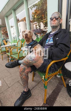 Inghilterra, Kent, Faversham, uomo tatuato seduto con cane in giro Foto Stock