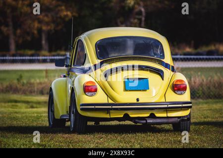 Piccola auto tedesca gialla seduta in un campo erboso in una pista da corsa. Foto Stock