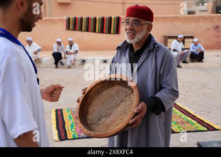 Un uomo Mozabite che mostra un vassoio di legno per un'asta in un tradizionale mercato all'interno di Ksar Bounoura. Valle di Mzab. Ghardaia Province.north Foto Stock