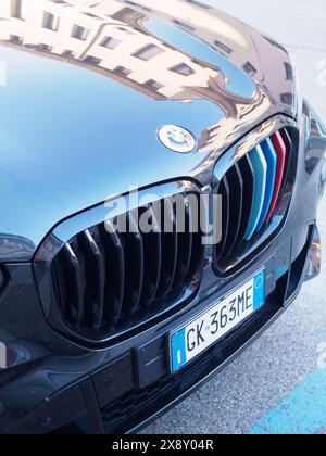 Cremona, Italia - 15 maggio 2024 foto ravvicinata della griglia anteriore e dell'emblema di un'auto bmw che riflette l'ambiente urbano, mostrando lusso e auto Foto Stock