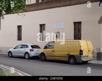 Cremona, Italia - 15 maggio 2024 il furgone giallo d'epoca è parcheggiato in una vecchia strada della città accanto a una moderna auto d'argento, che illustra diversi stili automobilistici Foto Stock