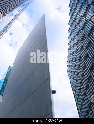 Impressionante architettura moderna a Londra con forme geometriche nitide e eleganti facciate in vetro che si affacciano verso il cielo. Foto Stock