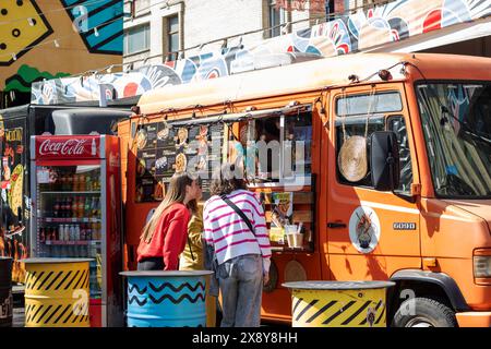 Bielorussia, Minsk - 5 maggio 2024: Una folla di persone si è riunita di fronte a un camion del cibo per gustare un pasto. La scena è piena di emozioni e l'aro Foto Stock