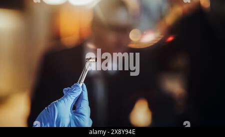 Primo piano estremo con sfondo sfocato: Mano con guanto medico utilizzando pinzette per tenere un guscio proiettile. Specialista forense che trova la cartuccia sulla scena del crimine e la mostra al detective come prova Foto Stock