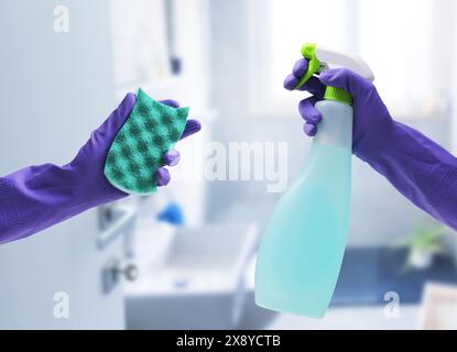 Mani femminili che indossano guanti in gomma e tengono in mano prodotti per la pulizia, bagno sullo sfondo, shot POV Foto Stock