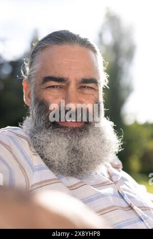 Un anziano caucasico che indossa una camicia a righe e sorride all'aperto Foto Stock