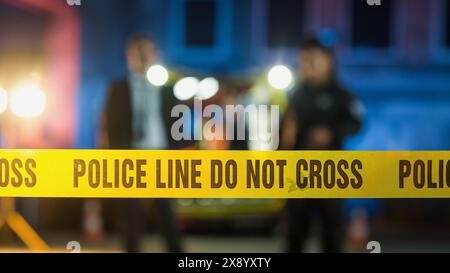 Nastri non incrociare che limitano l'accesso alla scena del crimine in una Back Alley. Detective che ispezionano il corpo e pensano al movente dell'assassino. CSI Team On Duty durante la notte Foto Stock