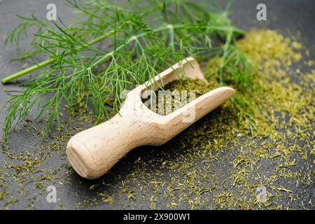 Aneto (Anethum graveolens var. hortorum), foglie di aneto essiccate e tritate con una pala di legno Foto Stock