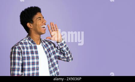 Attenzione! Giovane ragazzo in camicia a scacchi tenendo la mano vicino alla bocca Foto Stock