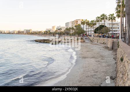 Cala Millor, Spagna; 13 aprile 2024: Vista generale di una baia con turisti sul lungomare della località turistica di Maiorca di Cala Millor al tramonto Foto Stock