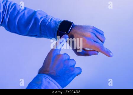 Uomo che controlla le notifiche sullo smartwatch con luce ambiente blu Foto Stock