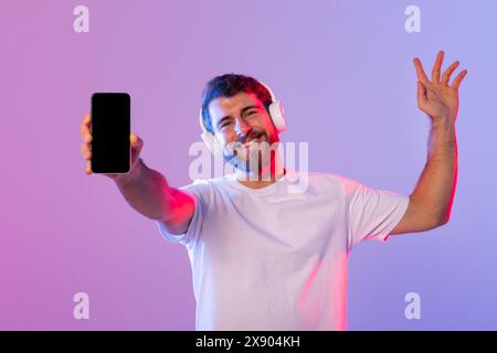 Uomo che indossa le cuffie che regge un telefono cellulare con schermo nero Foto Stock