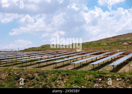 Una fattoria a energia solare è costruita su una collina sotto un cielo nuvoloso, circondata dalla natura, creando un luogo ecologico per generare energia in armonia Foto Stock