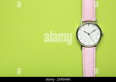 Orologi da polso rosa su sfondo verde con spazio di copia. Vista dall'alto Foto Stock