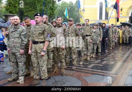 Convoglio militare di partecipanti alla guerra Russia-Ucraina in uniforme in attesa di Chiesa ortodossa Ucraina di Kiev Patriarcato croce processione, pioggia Foto Stock