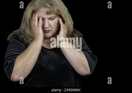 Questa immagine cattura un momento toccante di una donna bianca caucasica di 50 anni che soffre di depressione e di un grave mal di testa Foto Stock