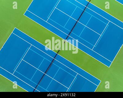 Aereo, drone, foto di un nuovo campo da tennis blu all'aperto con linee bianche combinate con linee da picchetto blu chiaro. Foto Stock