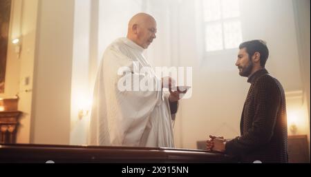 Il Vescovo rompe simbolicamente il Pane Comunale, che rappresenta il corpo di Cristo, e consegna i pezzi al parrocchiano. Ricordo del sacrificio altruista dei Salvatori. Santa Comunione, ultima cena, Eucaristia in Chiesa Foto Stock