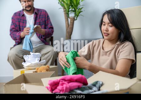 La giovane coppia si sta aiutando a vicenda a mettere in valigia oggetti per la casa per prepararsi a trasferirsi nella loro nuova casa Foto Stock