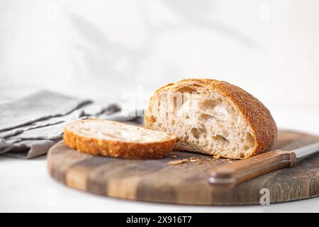 Pane artigianale appena sfornato Ciabatta su tagliere di legno in una cucina luminosa al mattino Foto Stock
