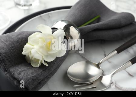 Ambiente elegante con posate, tovagliolo, fiori e piatti sul tavolo, primo piano Foto Stock