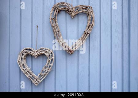 Due cuori di ramoscelli appesi su una porta di legno blu, Palatinato meridionale, Palatinato, Renania-Palatinato, Germania Foto Stock