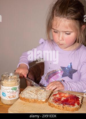 Bambino che prepara un sandwich al burro di arachidi e marmellata Foto Stock