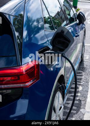 Un'auto elettrica parcheggiata in un punto di ricarica per veicoli elettrici su strada. Foto Stock