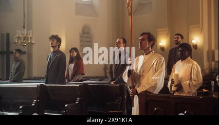 I ministri che portano Una Croce processuale, danno inizio alla liturgia della grande Chiesa. I parrocchiani si alzano pigramente mentre inizia la messa. Il servizio Eucaristico con sentita lode e adorazione da parte del popolo Foto Stock