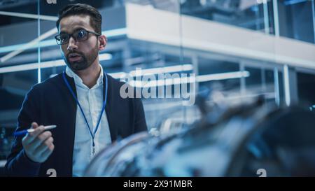 Smart Chief Engineer in occhiali che spiega la tecnologia avanzata di un'invenzione industriale moderna e innovativa a un team di studenti universitari in un corso universitario. Foto Stock