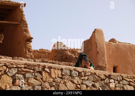 Turista che scatta fotografie con il suo telefono ad un ksar algerino a Taghit Foto Stock