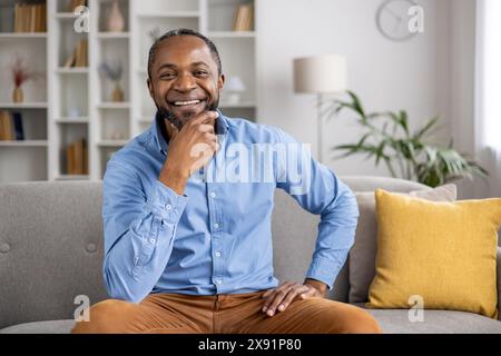 In un ambiente tranquillo, un uomo con un'espressione felice si rilassa in una camera piena di piante e libri, creando un ambiente accogliente e tranquillo per un momento di pace e comfort Foto Stock