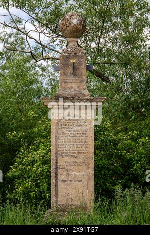 Monumento storico in pietra con testo inciso e una parte del quadrante solare del cavalcavia delle brughiere di Maud circondato dal verde in un ambiente rurale Foto Stock