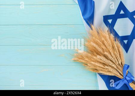 Storia ebraica Shavuot. Bouquet maturo di grano con nastro blu con bandiera israeliana e sfondi. Simboli del concetto Shavuot festivo ebraico. Indietro Foto Stock