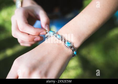 Una giovane donna espone un bracciale lazzuli in argento e lapislazzuli in un ambiente naturale all'aperto Foto Stock