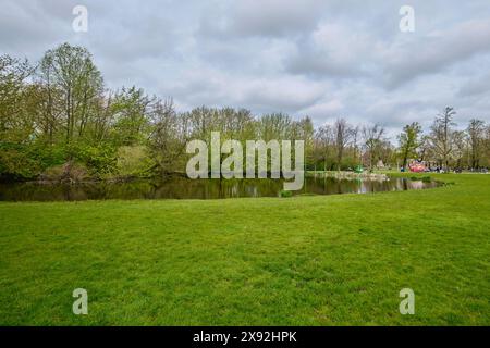 Paesi Bassi, Amsterdam - 10 aprile 2024: Campo di erba e stagno a Vondelpark. È un parco urbano pubblico di 47 ettari Foto Stock