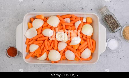 Ricetta per zuppa di zucca arrostita. Cubetti di zucca sbucciati e senza semi, carota, cipolla, aglio e spezie da vicino in una teglia da forno in ceramica inclusa nel kit Foto Stock
