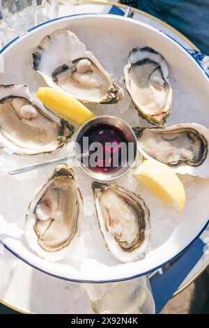 Deliziose ostriche crude servite su ghiaccio con salsa al limone e all'aceto Foto Stock