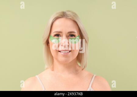 Bella donna matura felice con toppe sotto gli occhi su sfondo verde Foto Stock