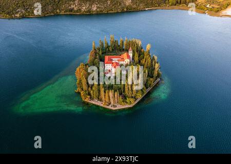 Visovac, Croazia - Vista aerea dell'incredibile monastero cristiano di Visovac nel Parco Nazionale di Krka in una luminosa mattinata d'estate con calde luci dorate a. Foto Stock