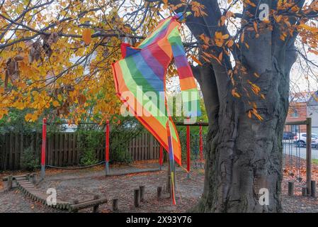 Un aquilone volante impigliato nei rami di un grande albero. Primo piano. Paesaggio urbano autunnale Foto Stock