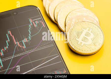 Moneta d'oro Bitcoin. Criptovaluta e grafico aziendale in un cellulare. Foto Stock