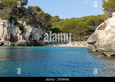 Minorca, Spagna - 6 settembre 2021: Cala de Macarelleta sull'isola di Minorca con le persone che fanno il bagno in vacanza circondato dalla vegetazione. Balearic sì Foto Stock