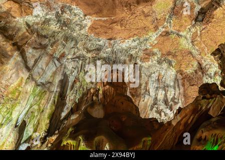 L'interno di una grotta è coperto di muschio e ha una tinta verdastra. I muri sono fatti di pietra e il soffitto è fatto di roccia. La grotta è buia e. Foto Stock
