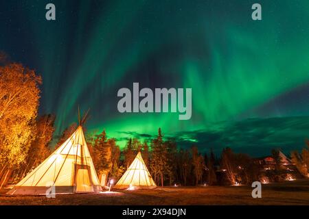 Incredibile aurora boreale che balla sopra la luce di tipi o Tepees all'Aurora Village di Yellowknife, territori del Nord-Ovest, Canada. Foto Stock